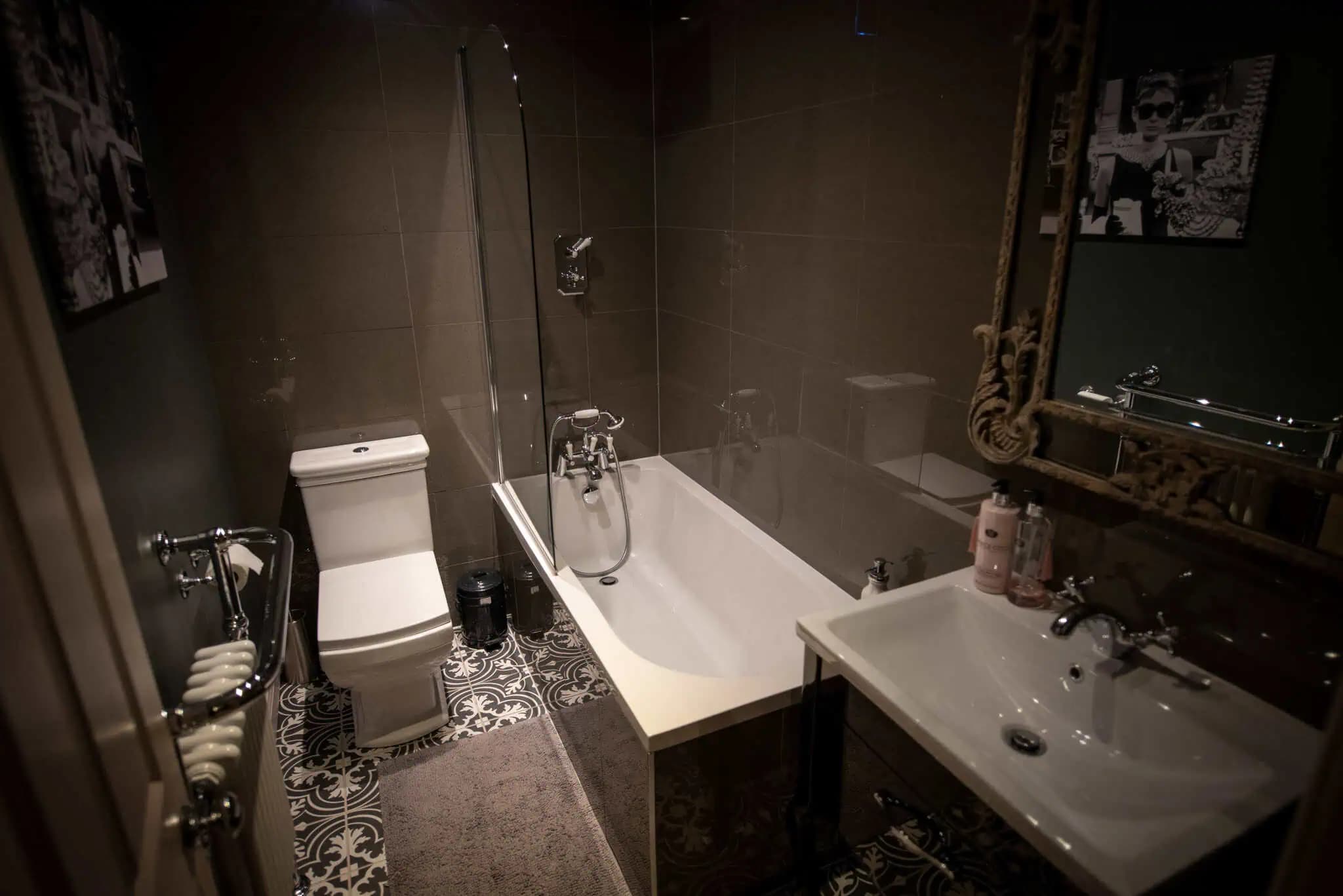 Bathroom with a bath and dark tiled walls inside Luxurious Home.