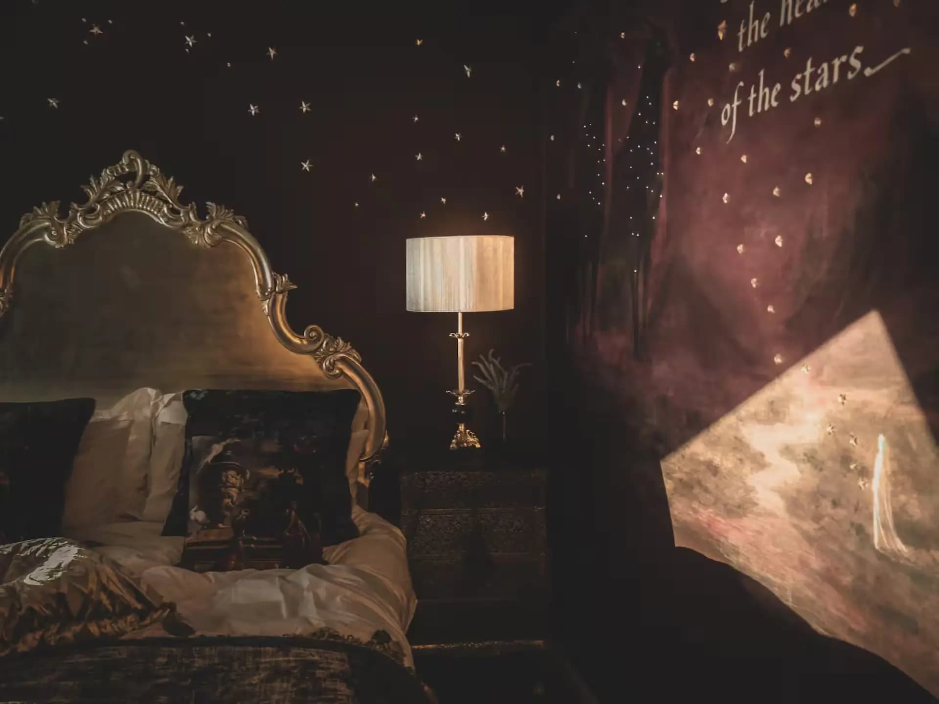 Ornate bed and bedside lamp beneath a starry mural inside Luxurious Home.