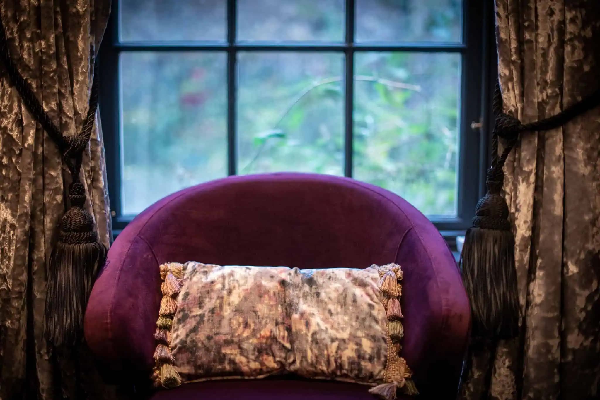 Purple chair by a bedroom window inside Luxurious Home.