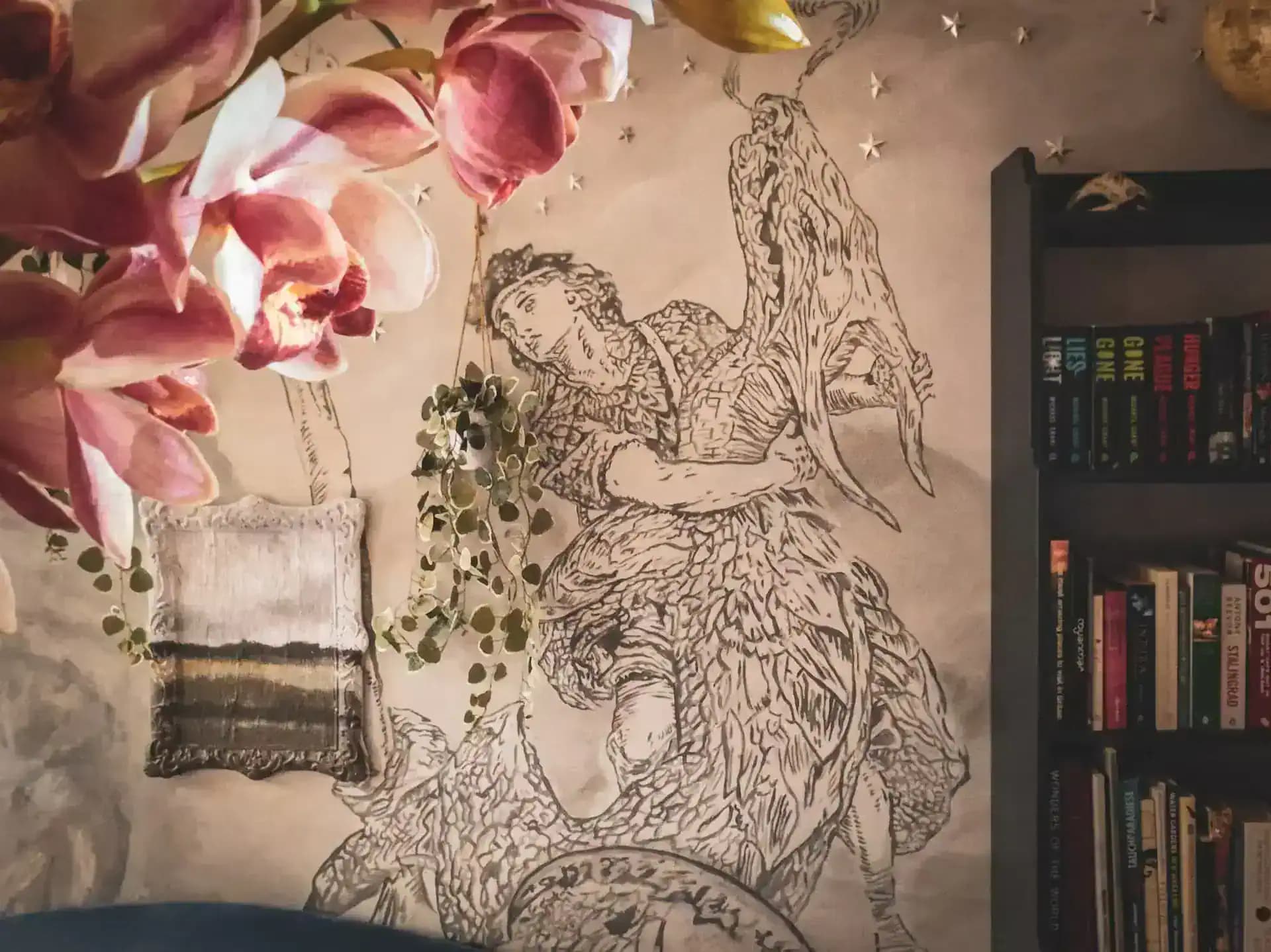Mural wall and flowers beside a bookcase inside Luxurious Home.